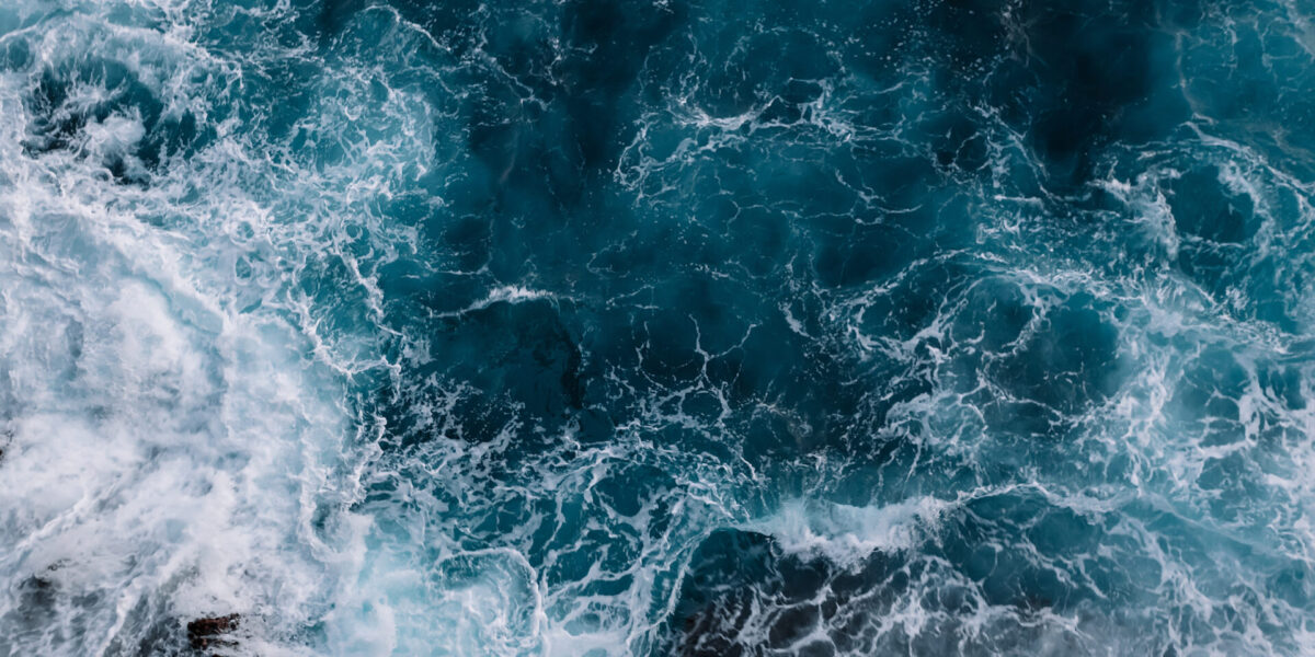 aerial view of white ocean waves against a blue water background