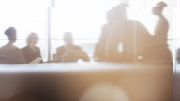 Silhouette of business people in meeting, focusing on data and reports to inform decision-making and policy