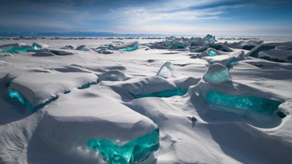 photo turquoise-colored ice under snowpack under a blue sky at Lake Baikal in Russia