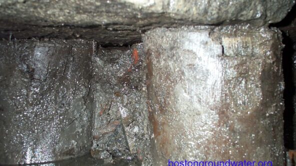 photo upclose look at old wood pilings below a historical building; low groundwater levels make pilings vulnerable to decay | credit Boston Groundwater Trust