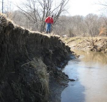 photo of State Geologist of Iowa and Director of the Iowa Geological Survey, Keith Schilling surveys severe erosion on Walnut Creek | photo credit Iowa Geological Survey