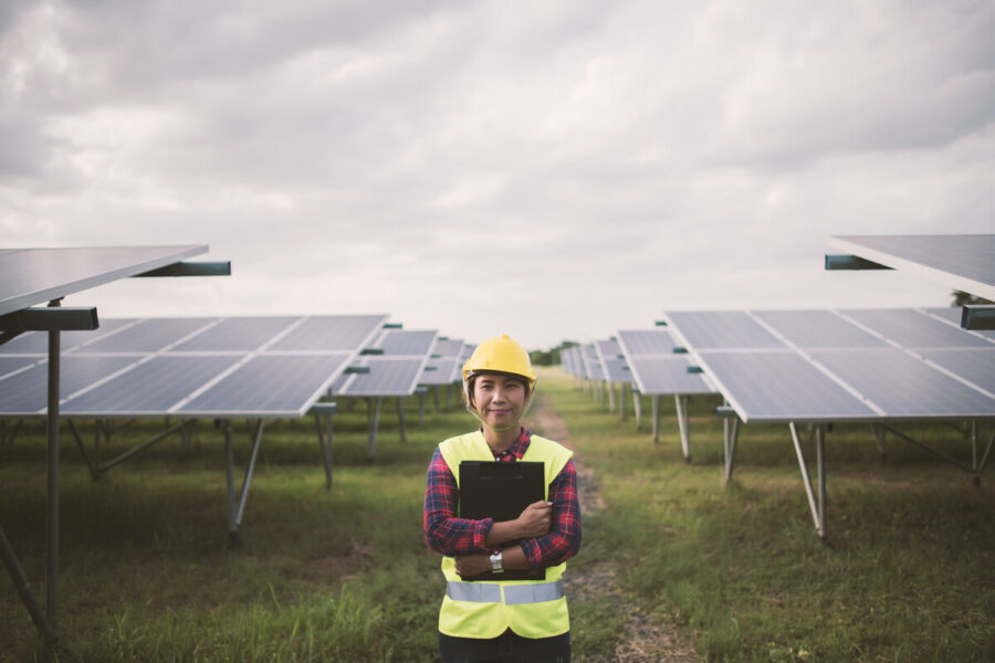 photo of female engineer with hardhat and tablet to inspect solar PV cells on a utility-scale solar farm