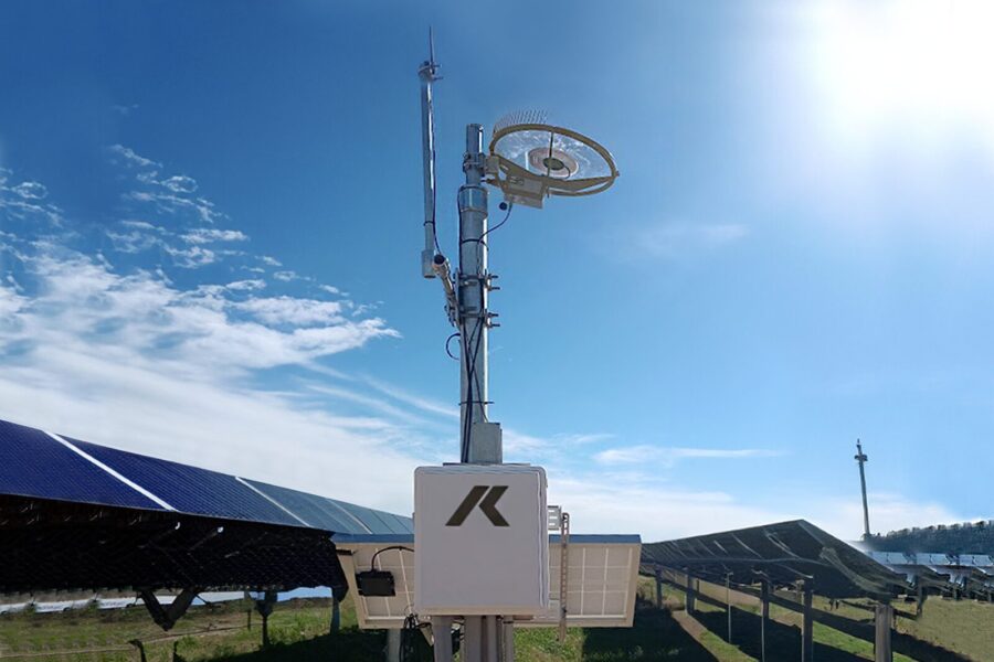 photo of HailSens IoT hail sensor mounted on a weather station amid rows of PV panels in a utility-scale solar generation facility